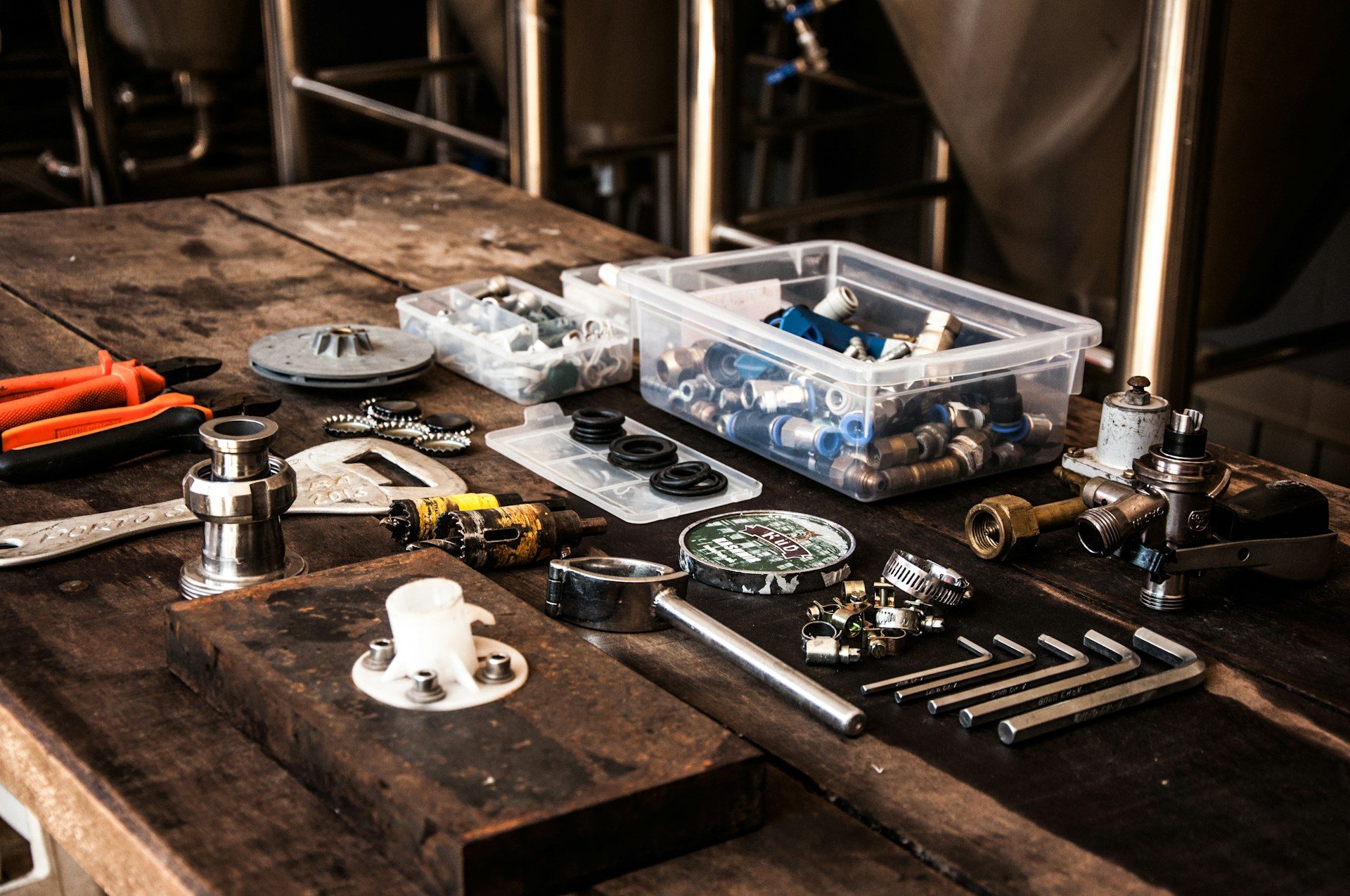 A workbench with hand tools, fittings and sorted parts bins laid out on it